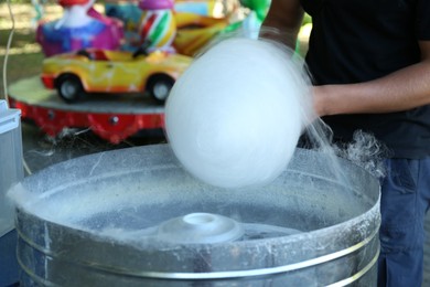 Photo of Man making cotton candy with machine outdoors, closeup