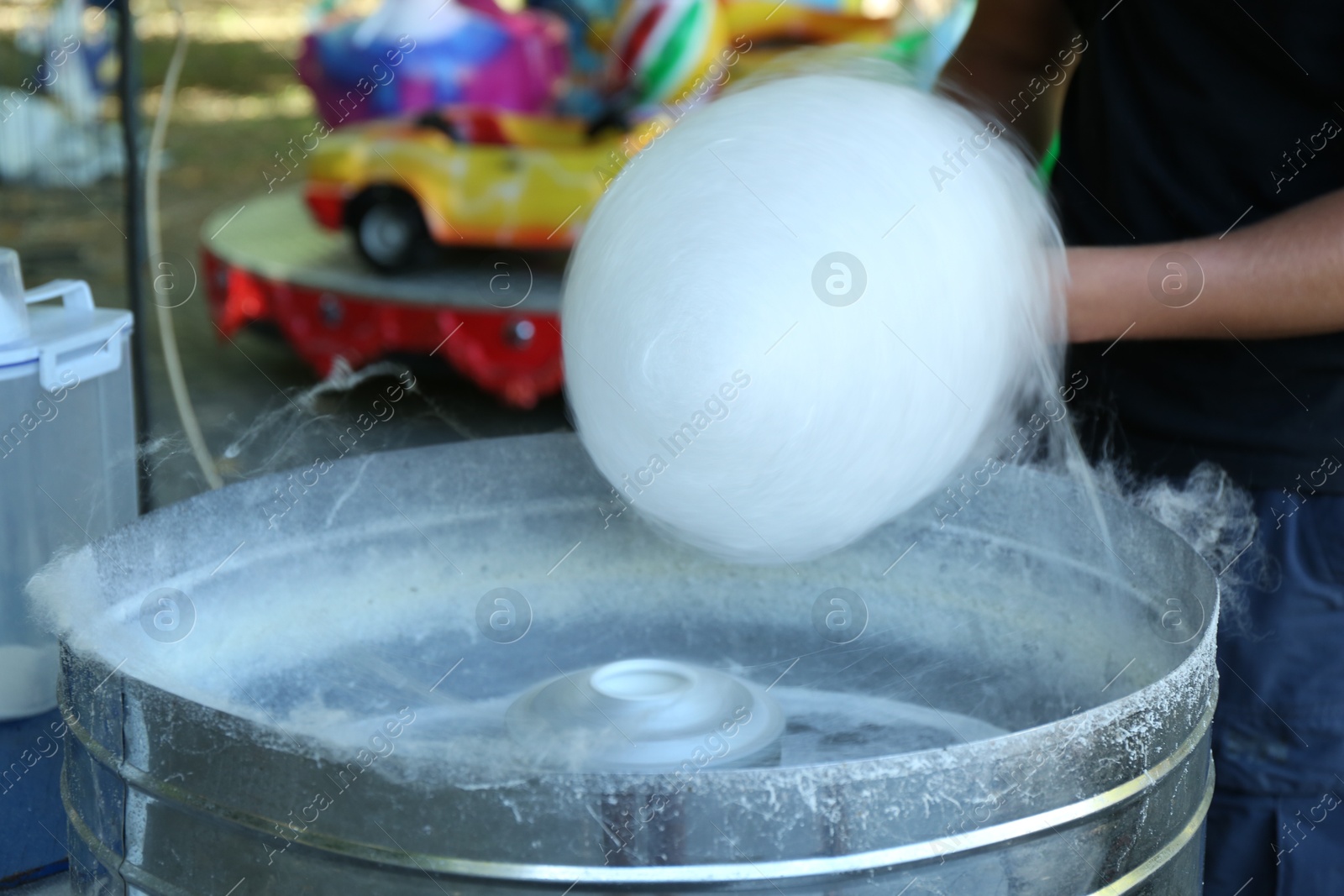 Photo of Man making cotton candy with machine outdoors, closeup