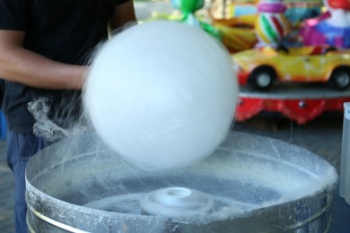 Photo of Man making cotton candy with machine outdoors, closeup