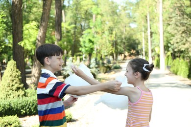 Photo of Little girl and boy eating sweet cotton candy in park