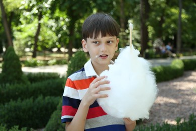 Photo of Portrait of little boy eating sweet cotton candy in park