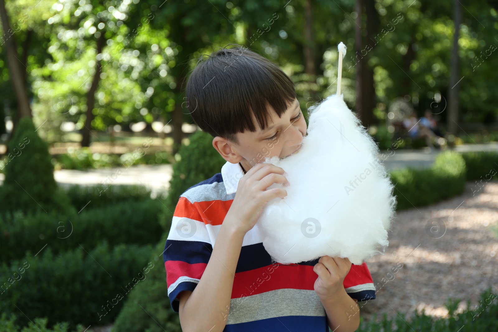 Photo of Portrait of little boy eating sweet cotton candy in park