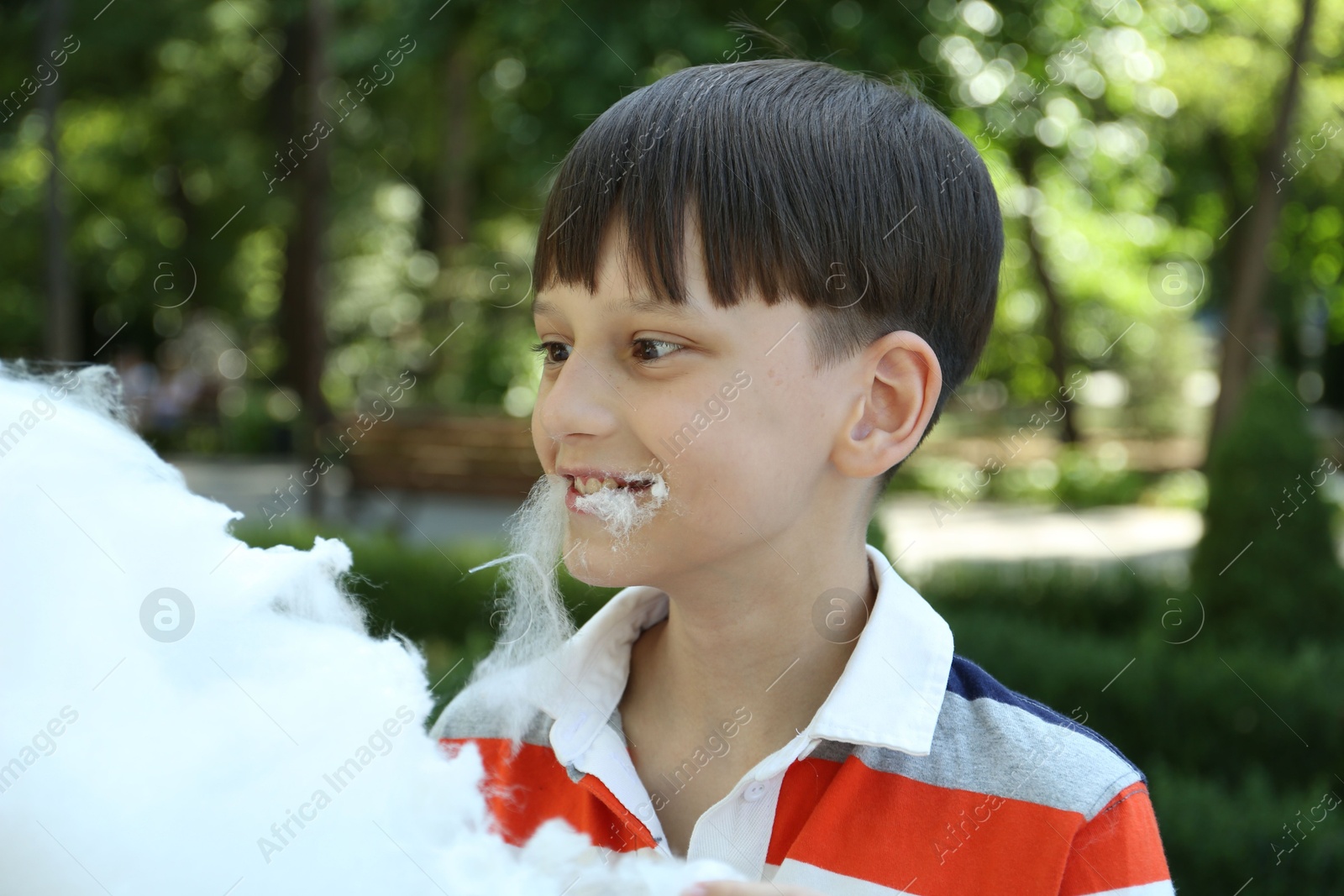 Photo of Portrait of little boy eating sweet cotton candy in park