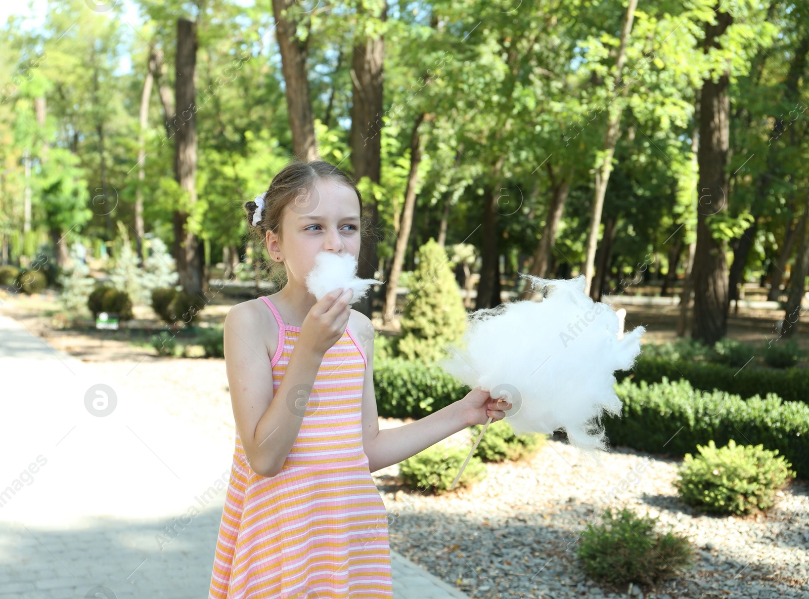 Photo of Portrait of little girl eating sweet cotton candy in park