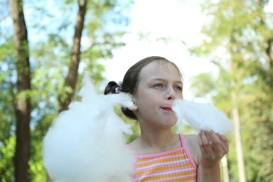 Photo of Portrait of little girl eating sweet cotton candy in park