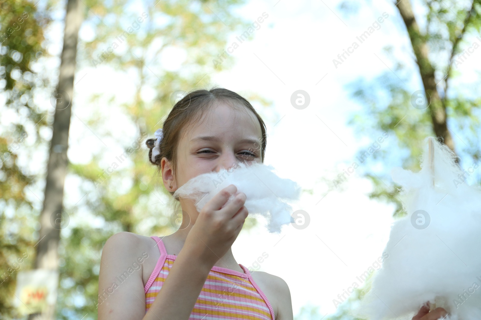 Photo of Portrait of little girl eating sweet cotton candy in park