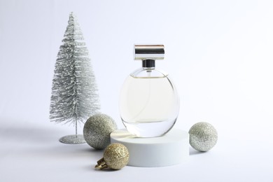 Stylish composition of perfume bottle and Christmas decor on white background