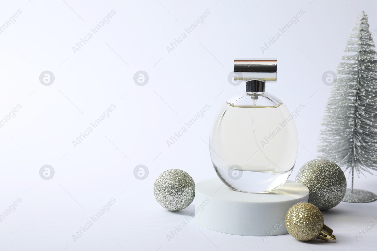 Photo of Stylish composition of perfume bottle and Christmas decor on white background. Space for text