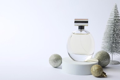 Photo of Stylish composition of perfume bottle and Christmas decor on white background. Space for text