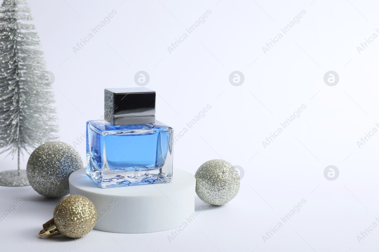 Photo of Stylish composition of perfume bottle and Christmas decor on white background. Space for text