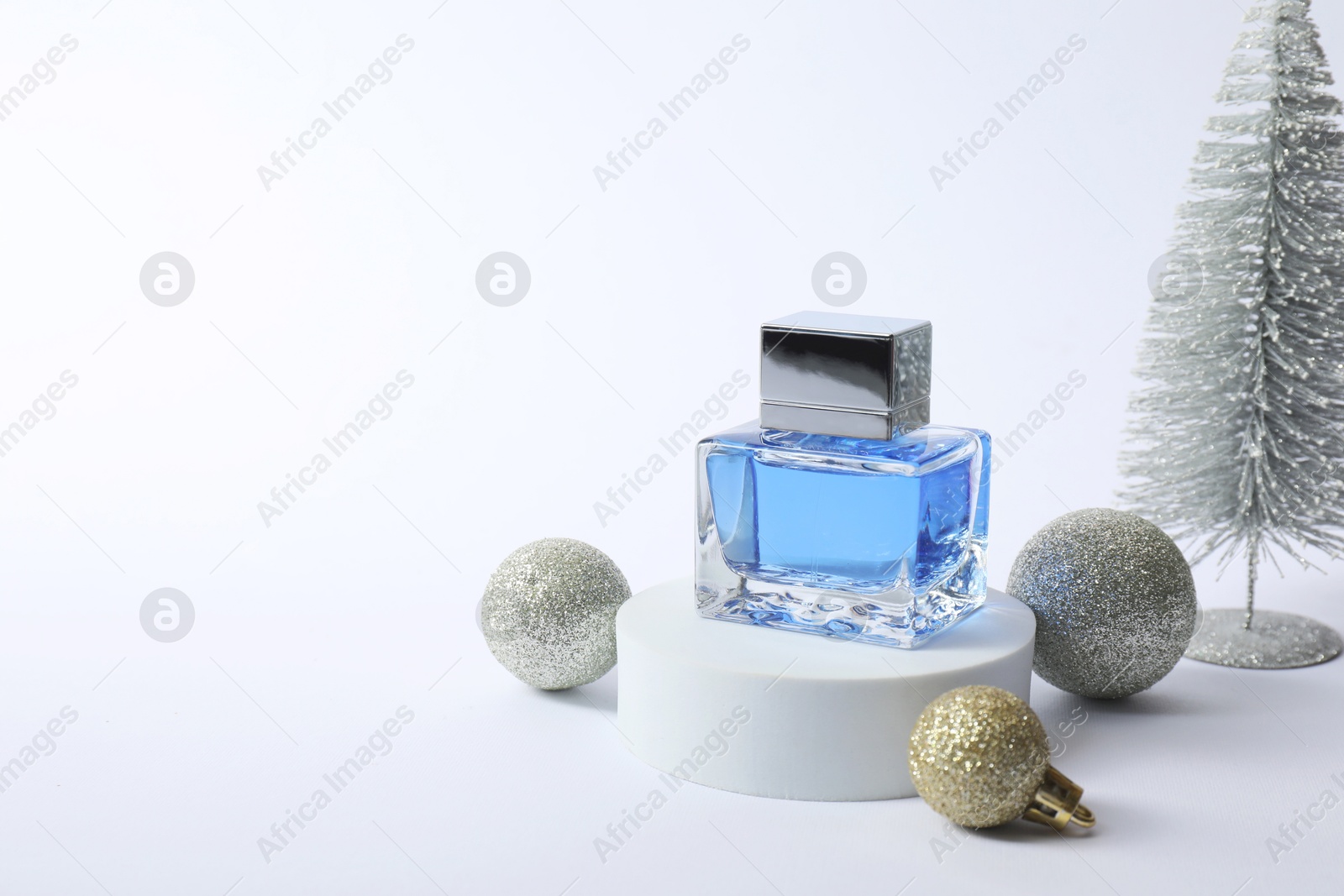 Photo of Stylish composition of perfume bottle and Christmas decor on white background. Space for text