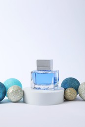 Photo of Christmas composition of perfume bottle and baubles on white background