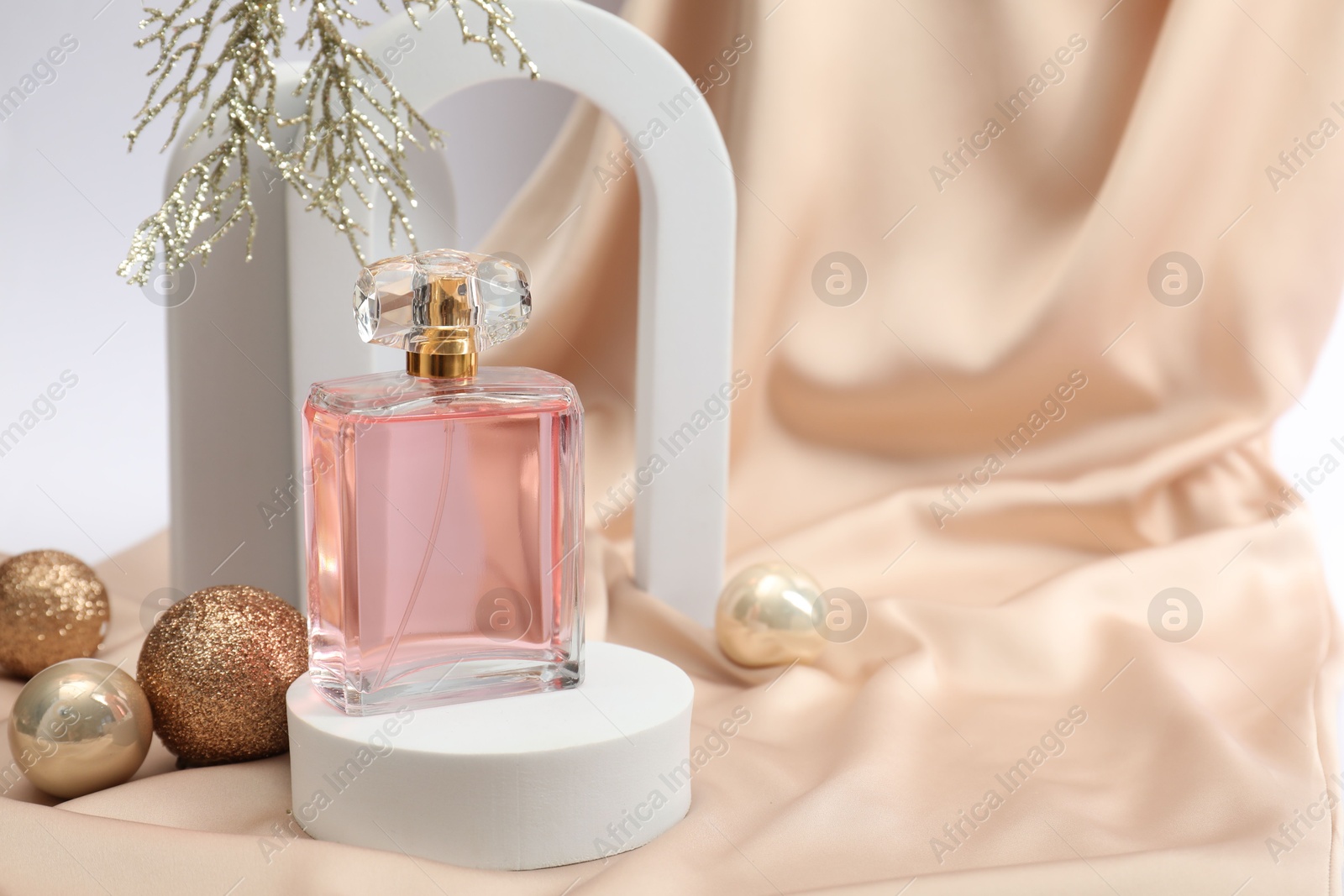 Photo of Stylish composition of perfume bottle and Christmas decor on white background. Space for text