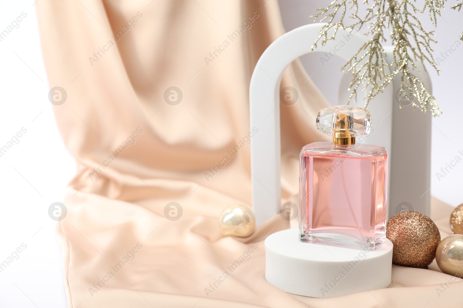 Photo of Stylish composition of perfume bottle and Christmas decor on white background. Space for text