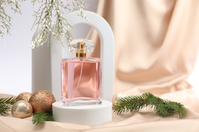 Photo of Stylish composition of perfume bottle and Christmas decor on white background. Space for text