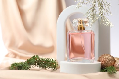 Stylish composition of perfume bottle and Christmas decor on white background. Space for text