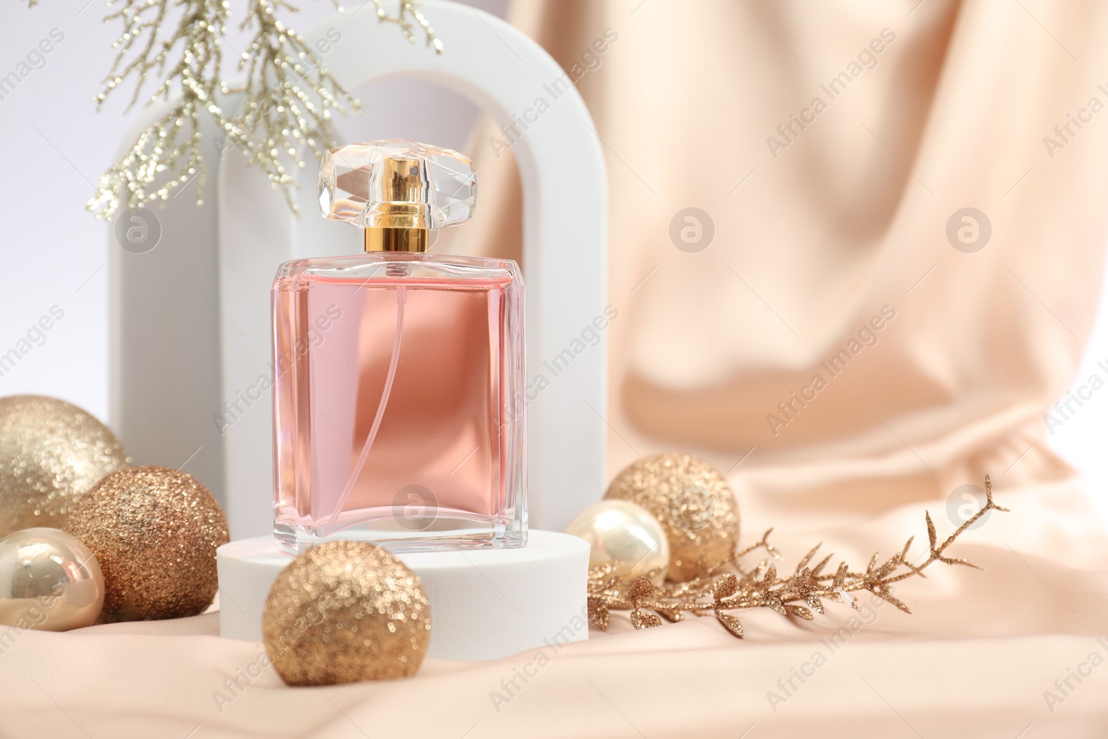 Photo of Stylish composition of perfume bottle and Christmas decor on white background. Space for text