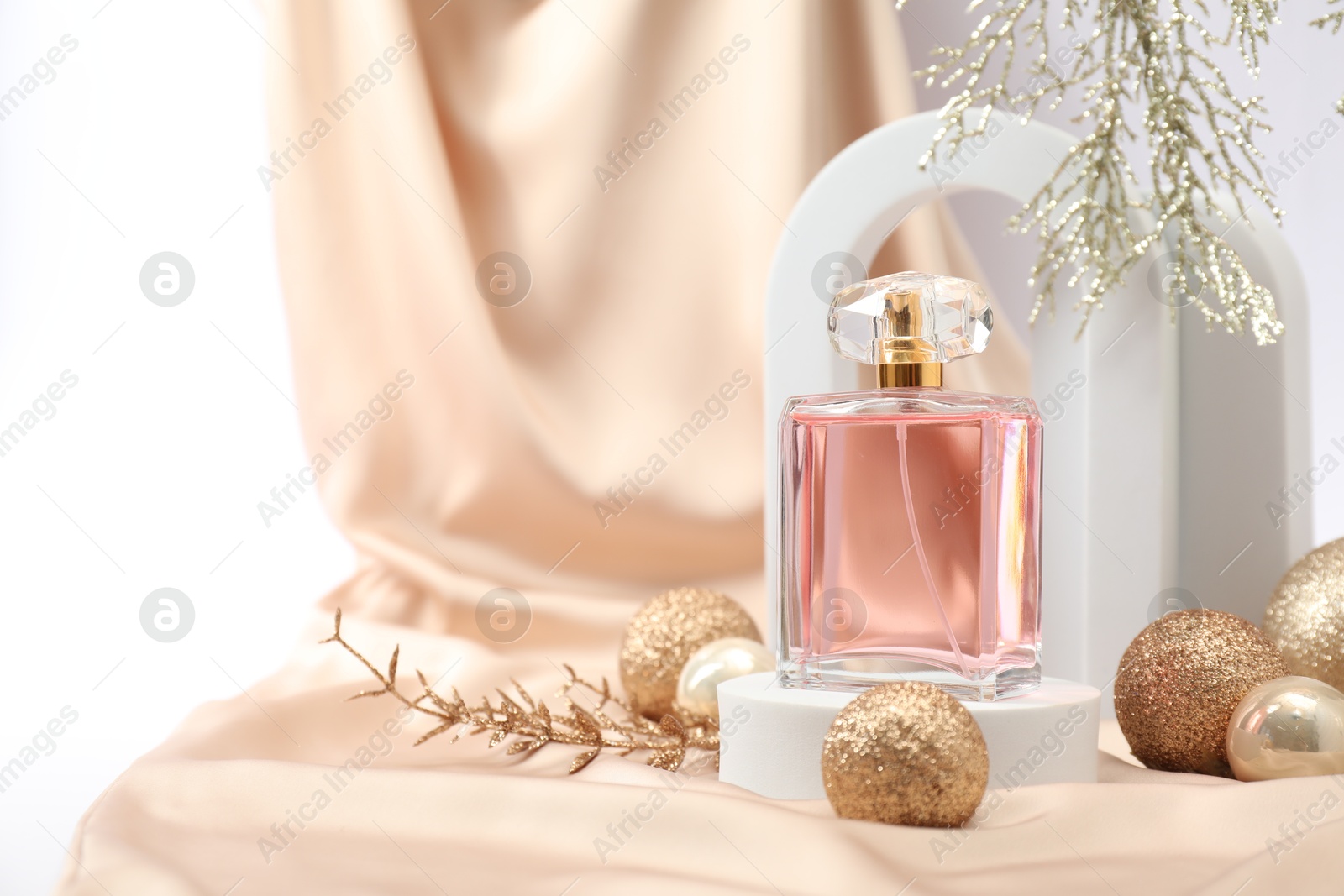 Photo of Stylish composition of perfume bottle and Christmas decor on white background. Space for text