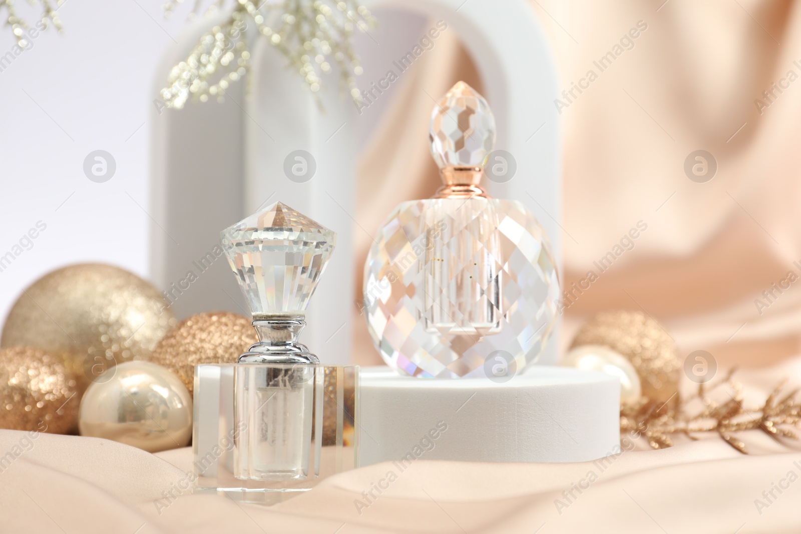 Photo of Stylish composition of perfume bottles and Christmas decor on beige cloth