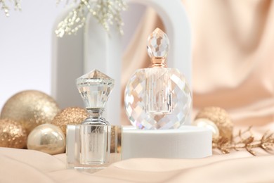 Photo of Stylish composition of perfume bottles and Christmas decor on beige cloth