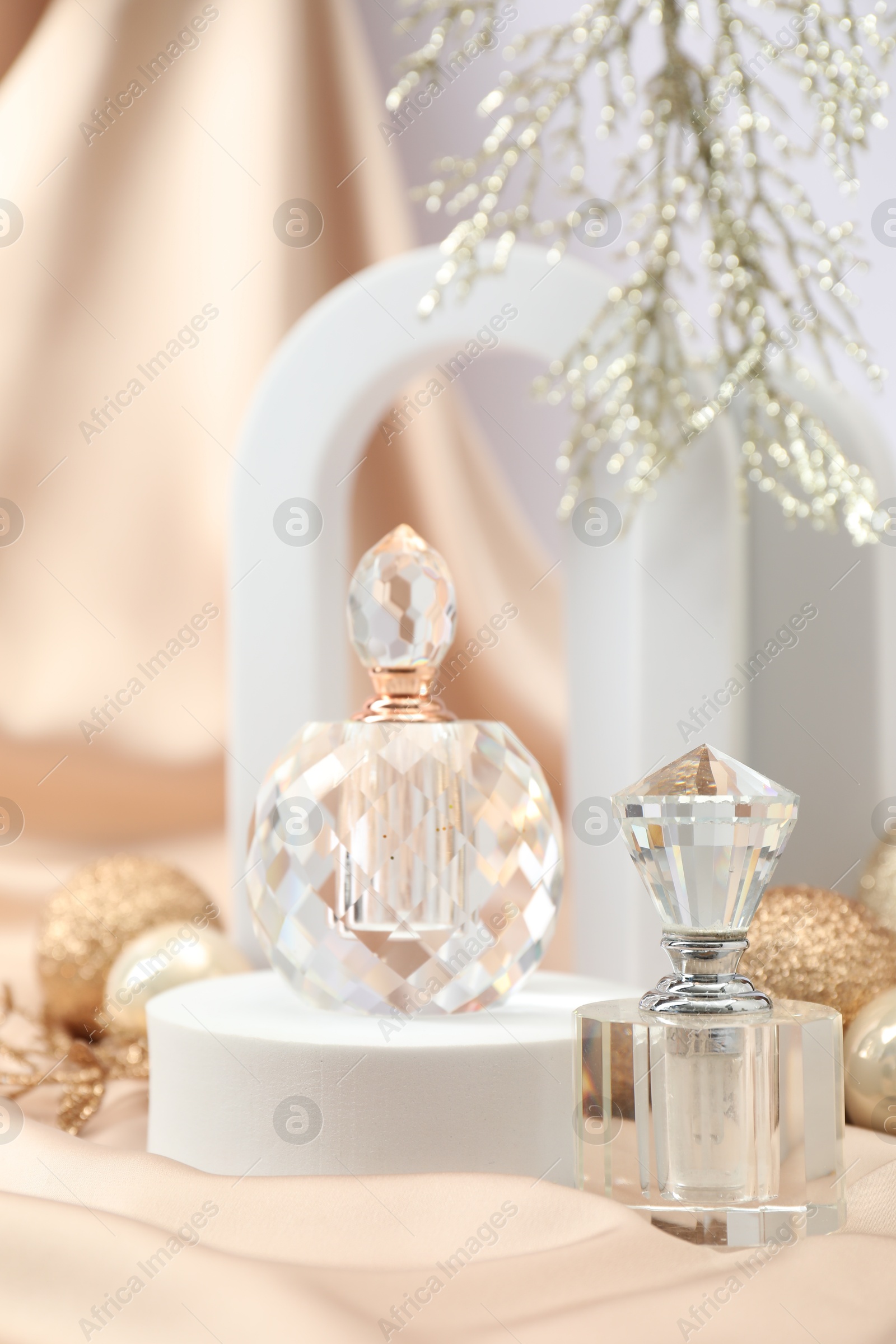 Photo of Stylish composition of perfume bottles and Christmas decor on beige cloth