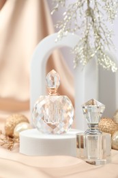 Stylish composition of perfume bottles and Christmas decor on beige cloth