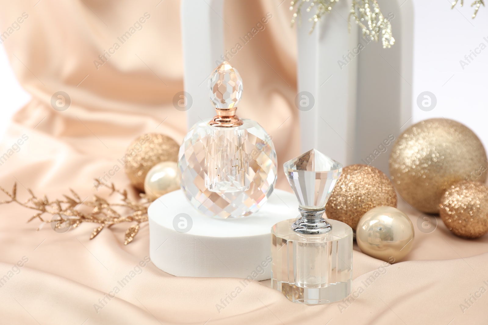 Photo of Stylish composition of perfume bottles and Christmas decor on beige cloth