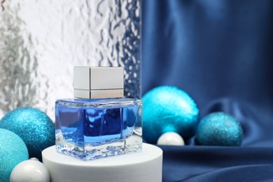 Photo of Stylish composition of perfume bottle and baubles on blue cloth