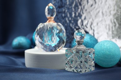 Photo of Stylish composition of perfume bottles and baubles on blue cloth