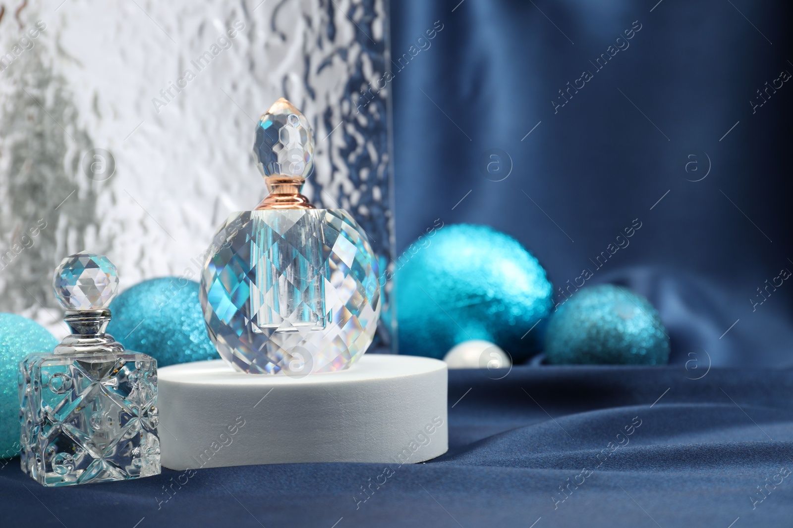 Photo of Stylish composition of perfume bottles and baubles on blue cloth. Space for text