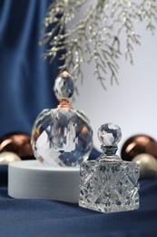 Photo of Stylish composition of perfume bottles and Christmas decor on blue cloth