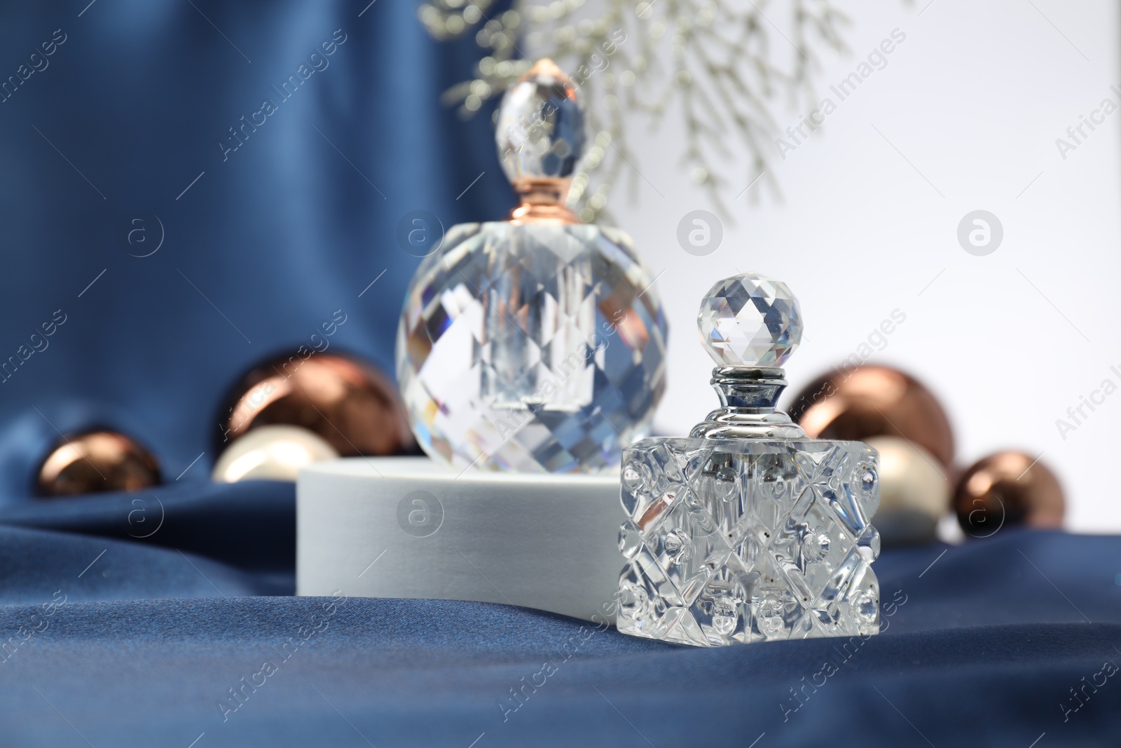 Photo of Stylish composition of perfume bottles and Christmas decor on blue cloth