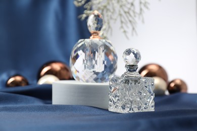 Photo of Stylish composition of perfume bottles and Christmas decor on blue cloth