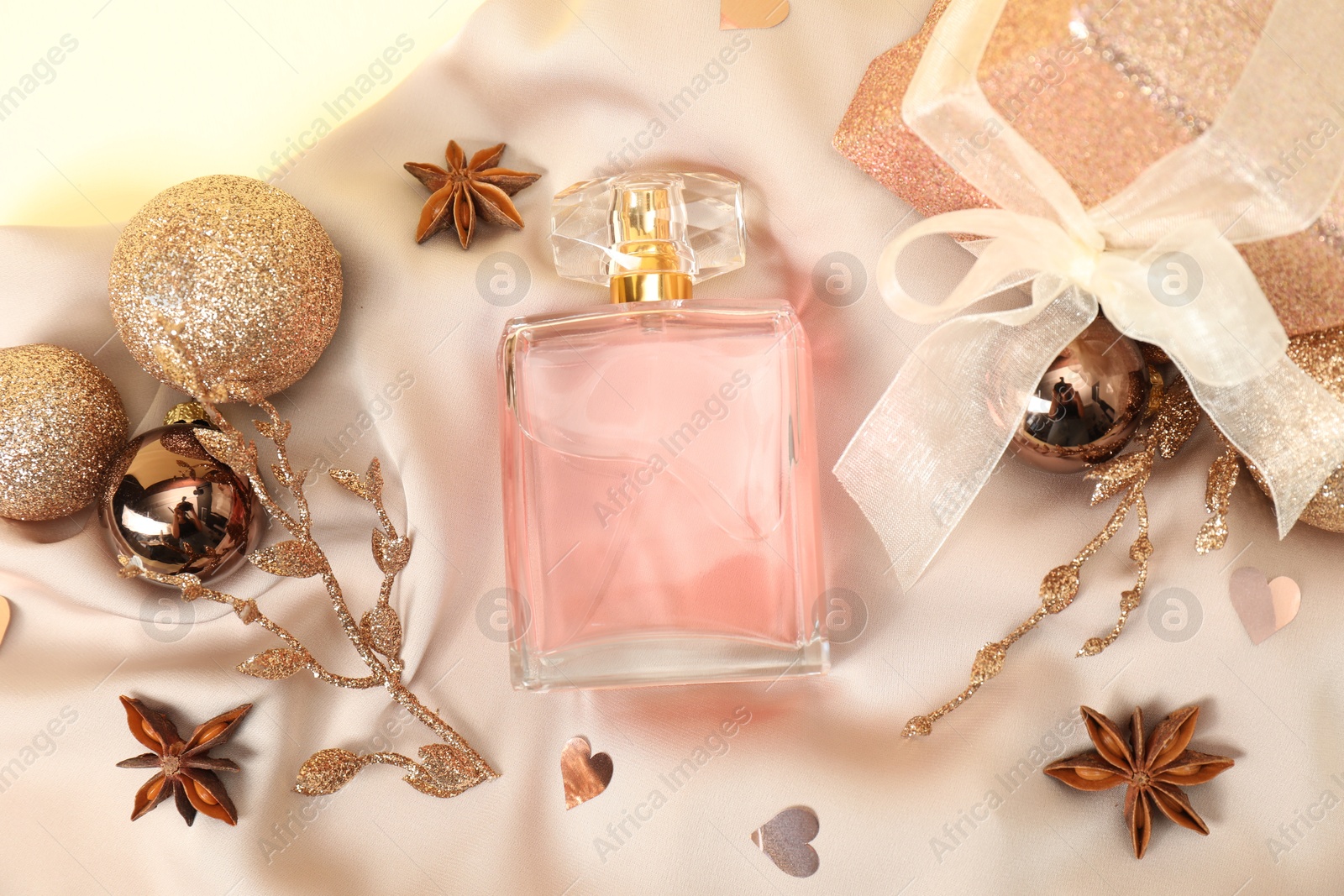 Photo of Christmas composition with perfume bottle on beige cloth, flat lay