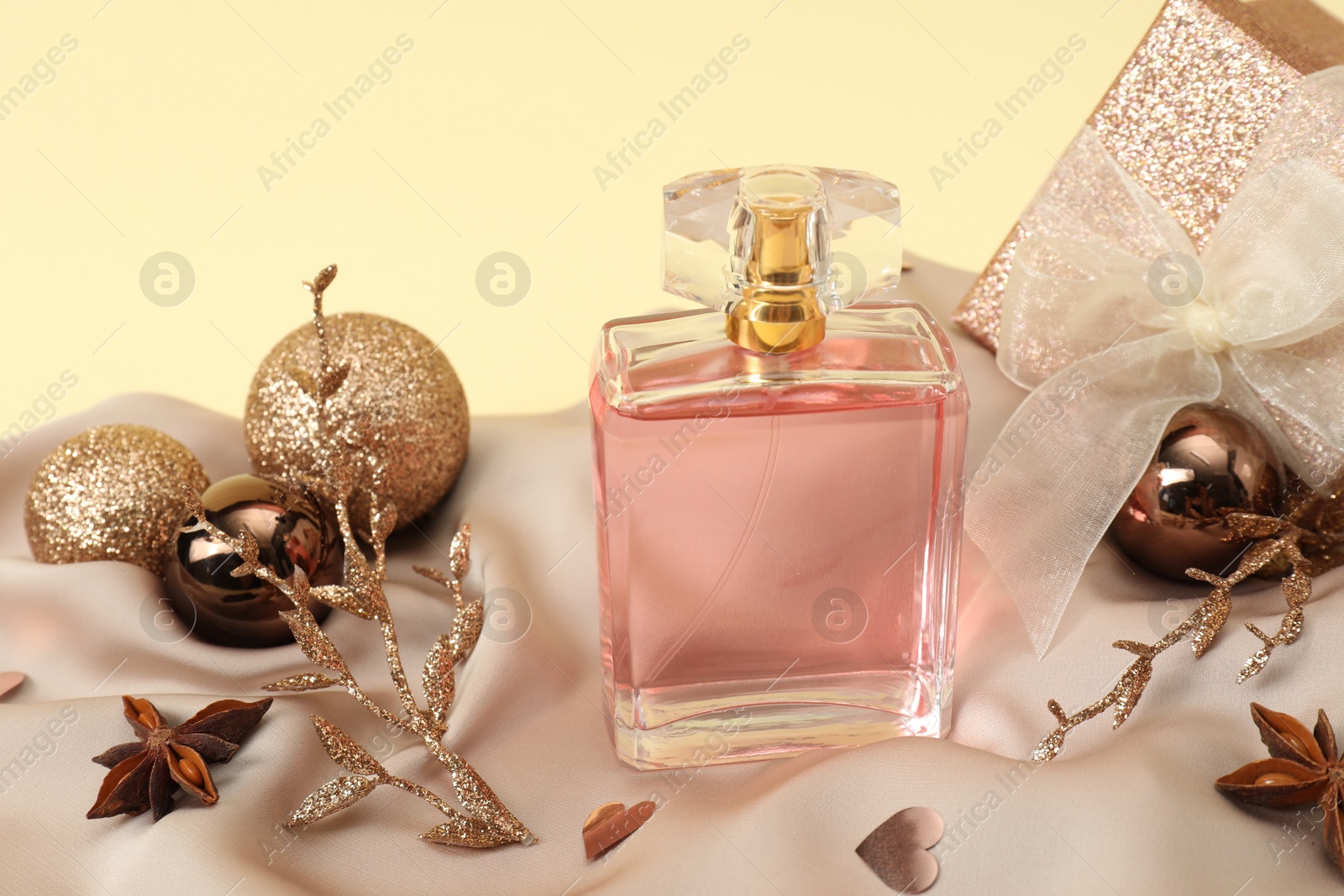 Photo of Stylish composition of perfume bottle and Christmas decor on beige background