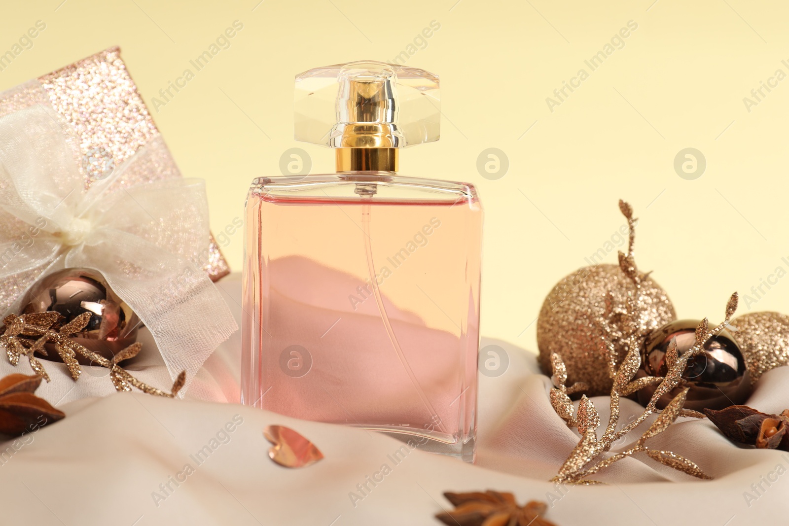 Photo of Stylish composition of perfume bottle and Christmas decor on beige background