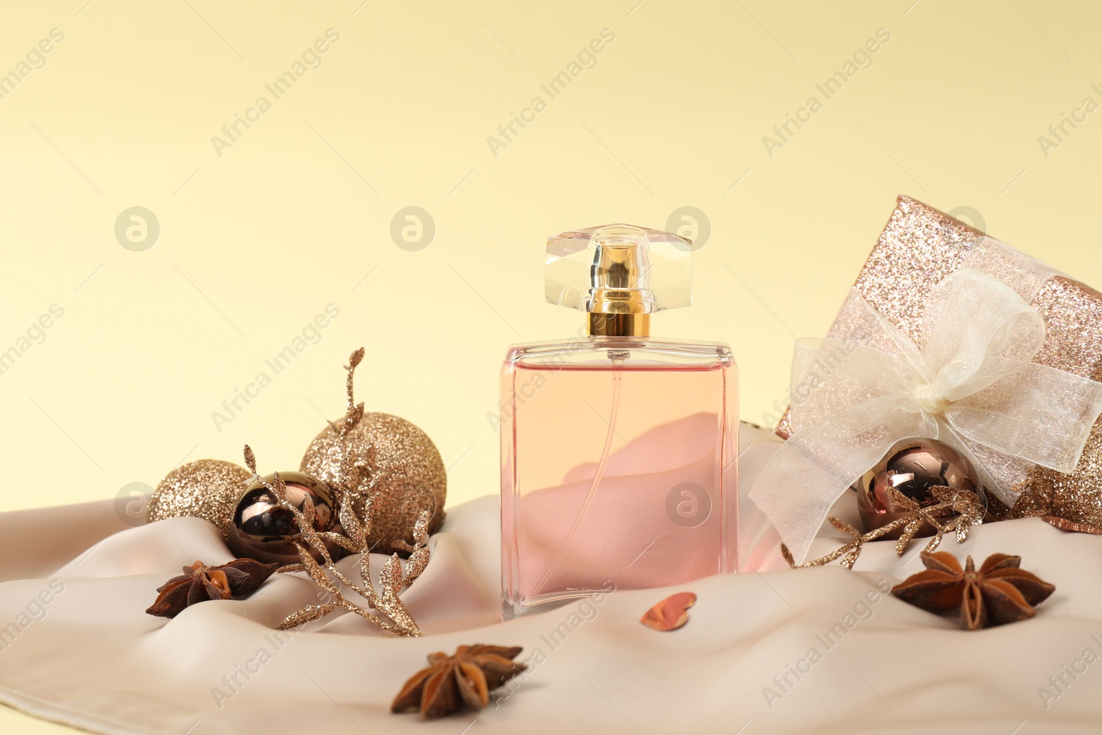 Photo of Stylish composition of perfume bottle and Christmas decor on beige background