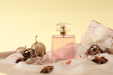 Photo of Stylish composition of perfume bottle and Christmas decor on beige background