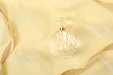 Photo of Stylish composition of perfume bottle and ribbons on beige background, top view