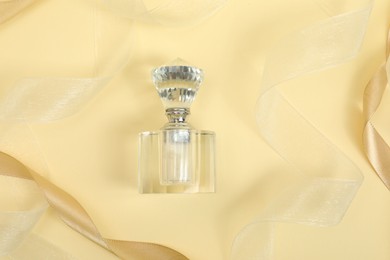 Photo of Stylish composition of perfume bottle and ribbons on beige background, top view