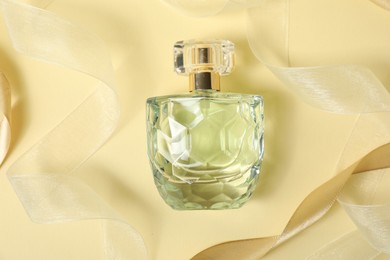 Photo of Stylish composition of perfume bottle and ribbons on beige background, top view