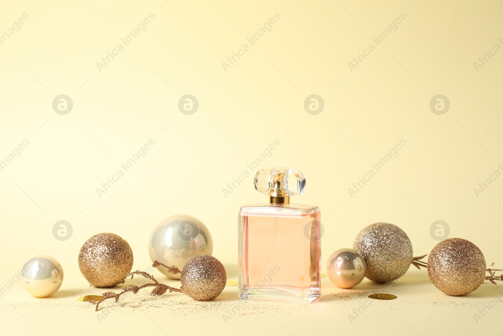 Photo of Stylish composition of perfume bottle and baubles on beige background. Space for text