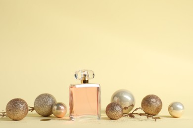 Photo of Stylish composition of perfume bottle and baubles on beige background. Space for text