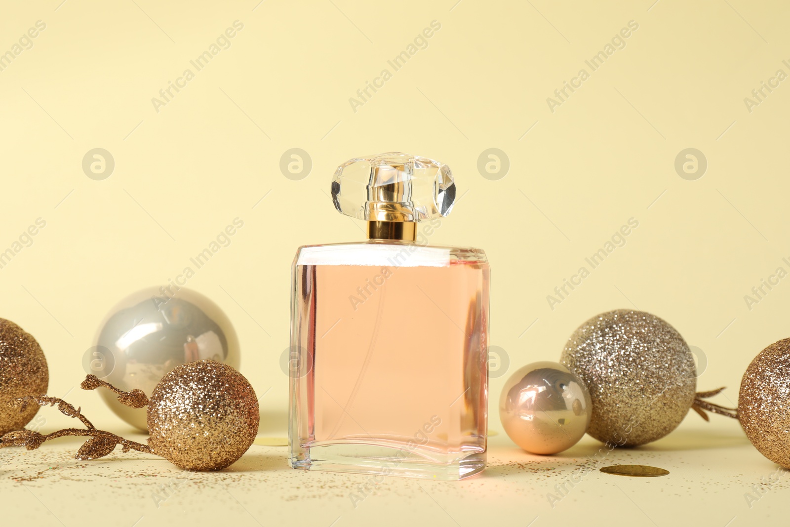 Photo of Stylish composition of perfume bottle and baubles on beige background