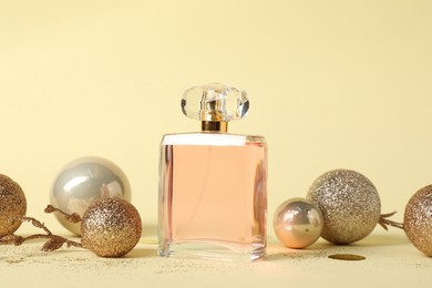 Stylish composition of perfume bottle and baubles on beige background