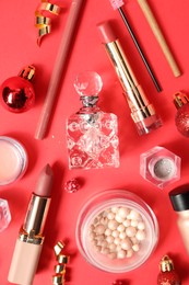 Photo of Christmas composition of perfume bottle and other cosmetics on red background, flat lay