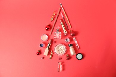 Christmas tree made of perfume bottles and makeup products on red background, flat lay