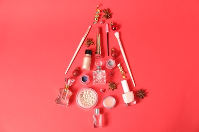 Christmas tree made of perfume bottles and makeup products on red background, flat lay