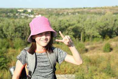 Photo of Portrait of little girl showing peace sign outdoors on sunny day. Space for text