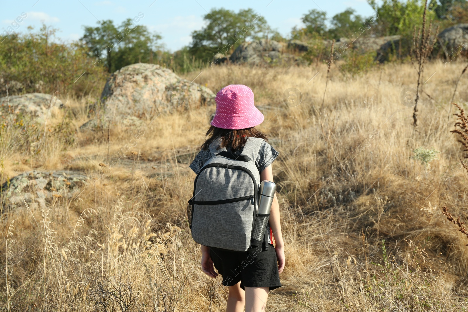 Photo of Little girl travelling at field, back view